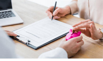 partial view of doctor holding piggy bank in hand while woman holding coin and signing document