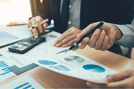 Manager calculates about the company finances by pressing on the calculator on the table with the employee explaining the summary report of the company cost at the office.