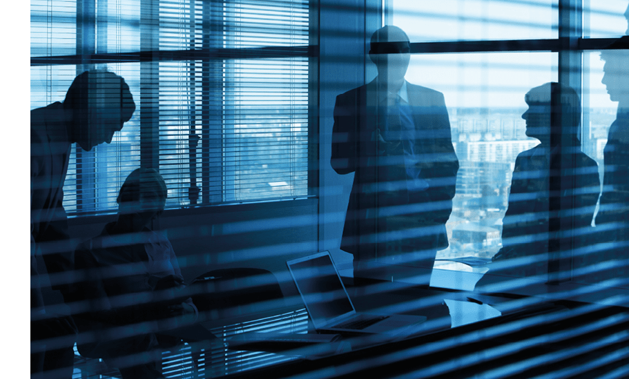 Darkened image of an office and five people in it viewed through jalousie