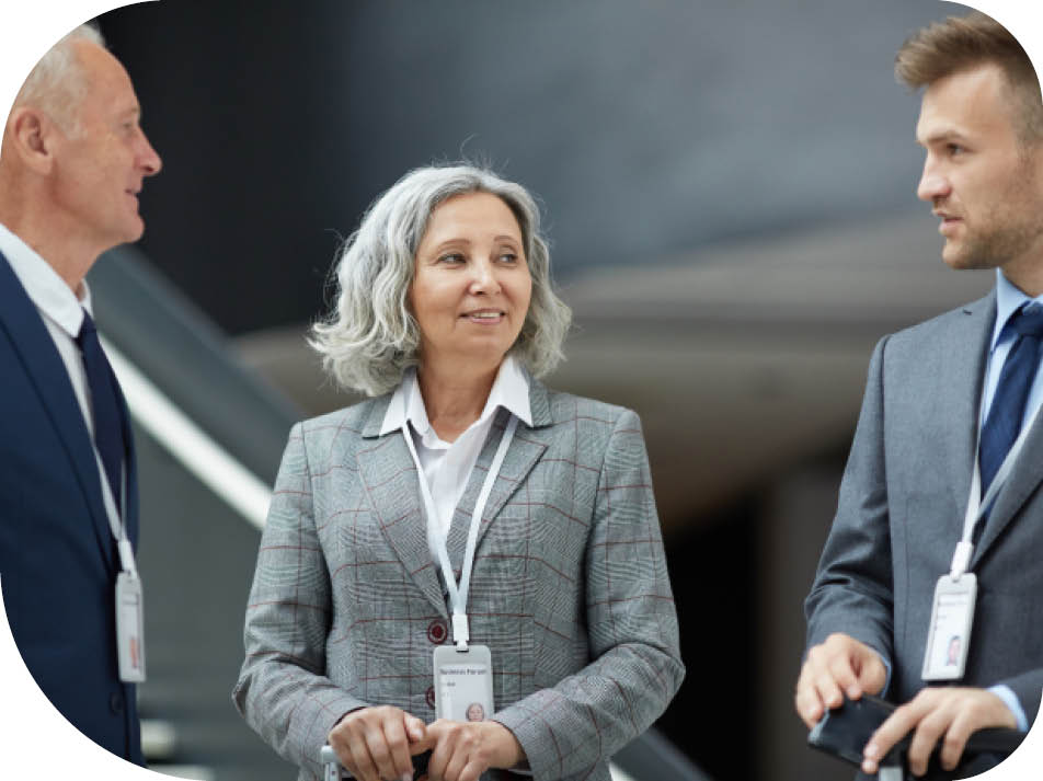 Content multi-ethnic participants of business forum wearing badges on ribbons talking in lobby