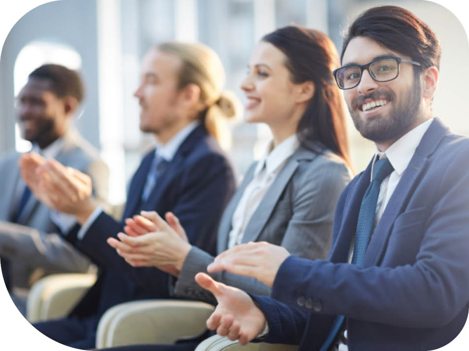 Happy excited young mixed race businessman in dark blue suit applauding at forum and looking at camera
