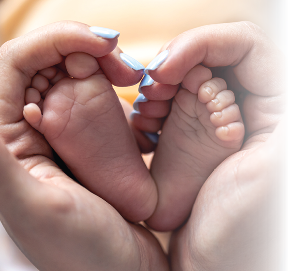 Mom holds the legs of a newborn baby in her hands, close-up, soft focus, concept of motherhood and care.