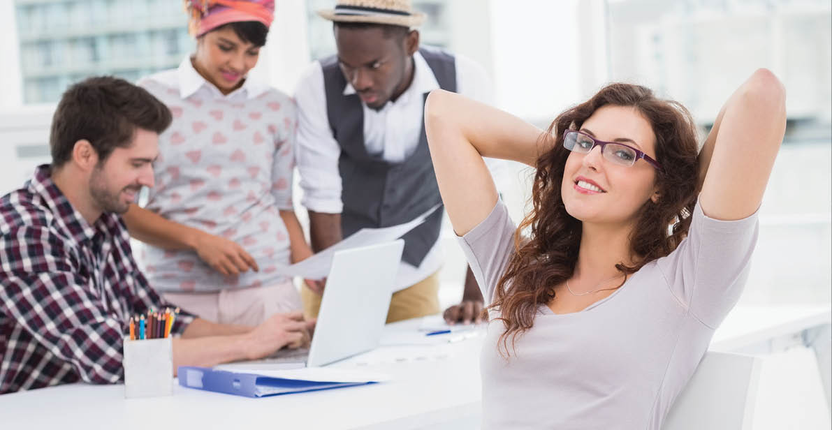 Portrait of relaxed businesswoman sitting with colleagues behind her